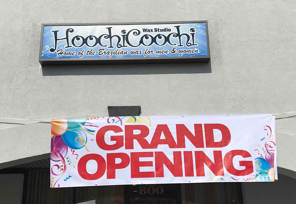 Grand opening banner beneath a HoochiCoochi Wax Studio sign